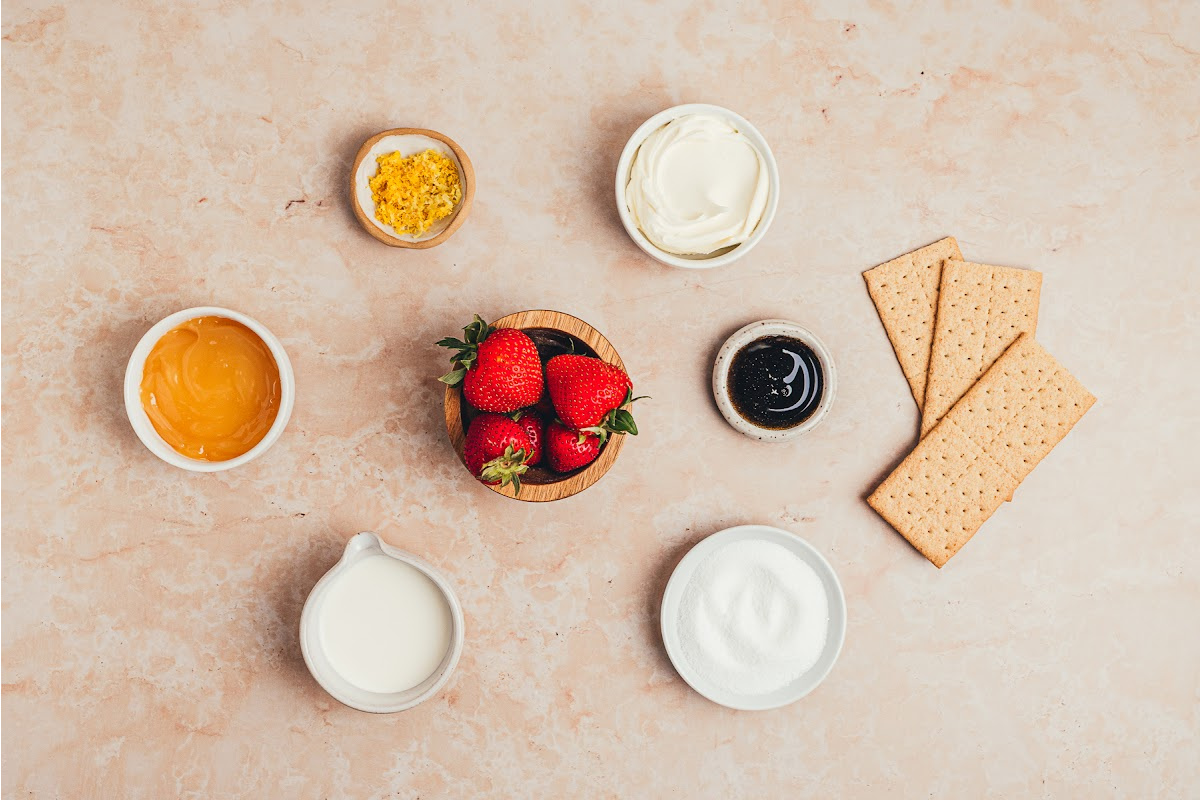 Ingredients for strawberry lemon icebox cake including mascarpone, lemon curd, strawberries, graham crackers, cream, vanilla, sugar, and lemon zest.