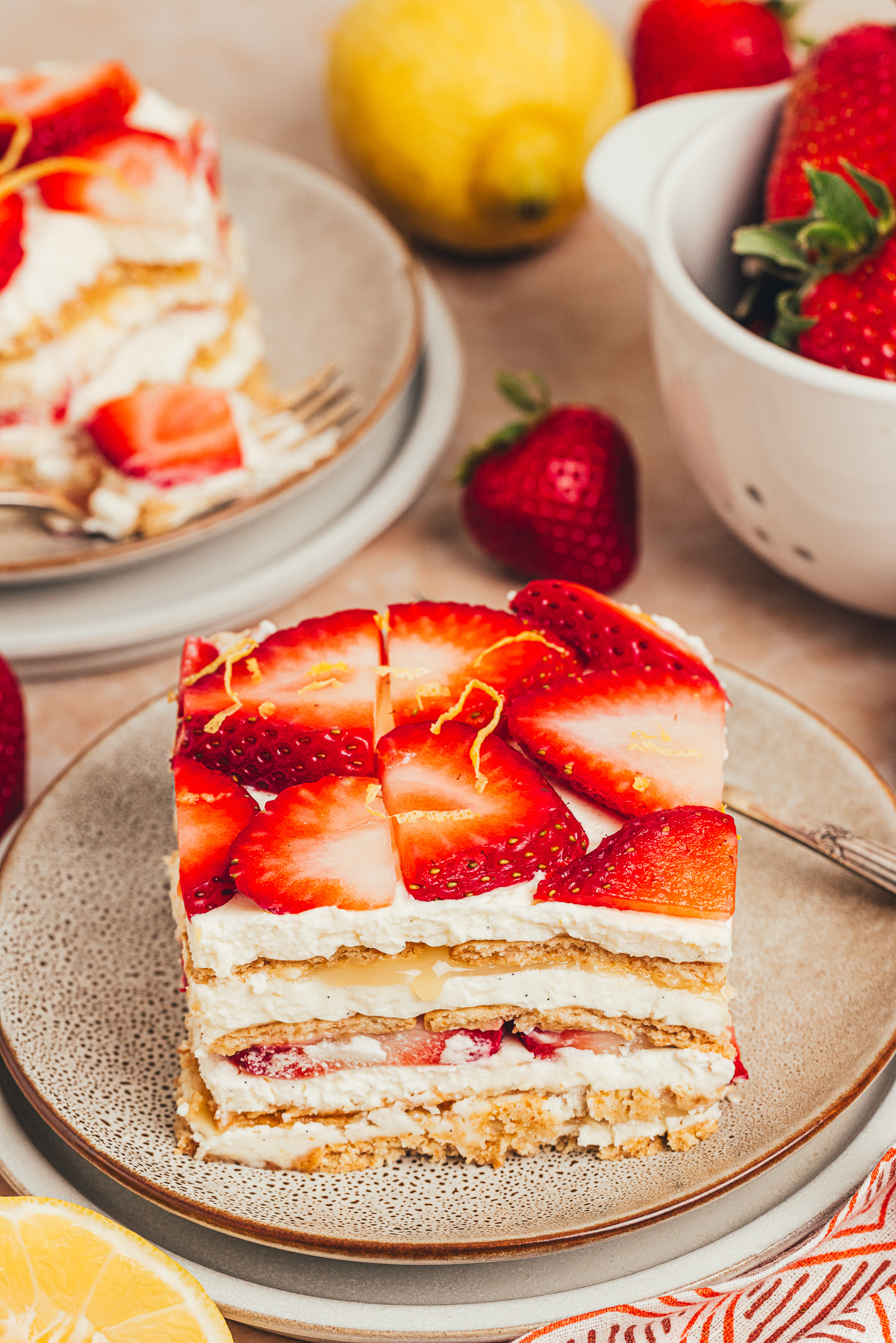 Slice of strawberry lemon icebox cake on a plate with mascarpone cream, lemon curd, strawberries, and softened graham cracker layers.