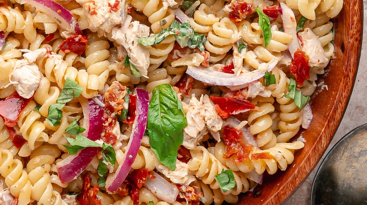 Sun-Dried Tomato Chicken Pasta Salad with basil, rotisserie chicken, red onion, and a glossy dressing made with oil-packed sun-dried tomatoes