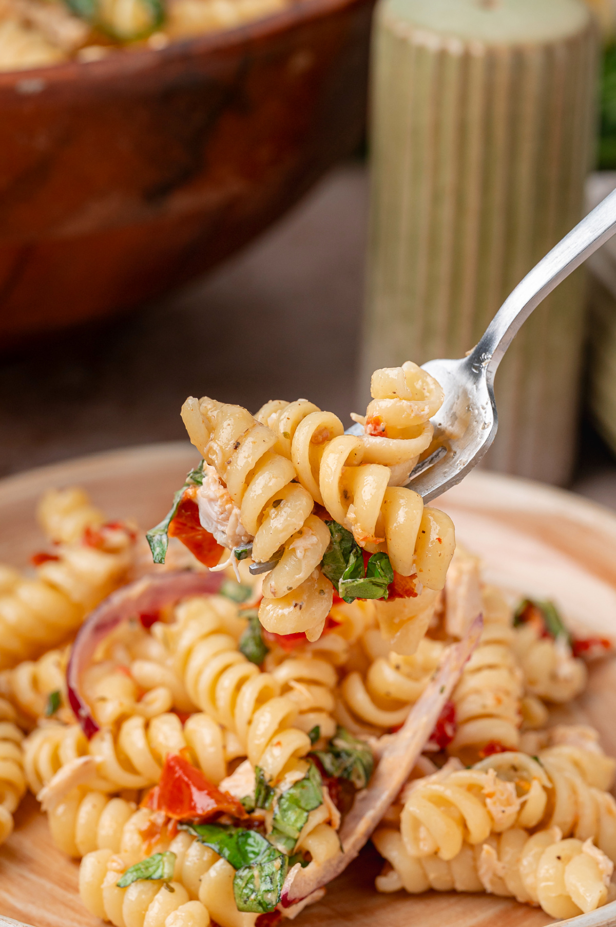 Forkful of Sun-Dried Tomato Chicken Pasta Salad with rotini, basil, red onion, and chopped sun-dried tomatoes