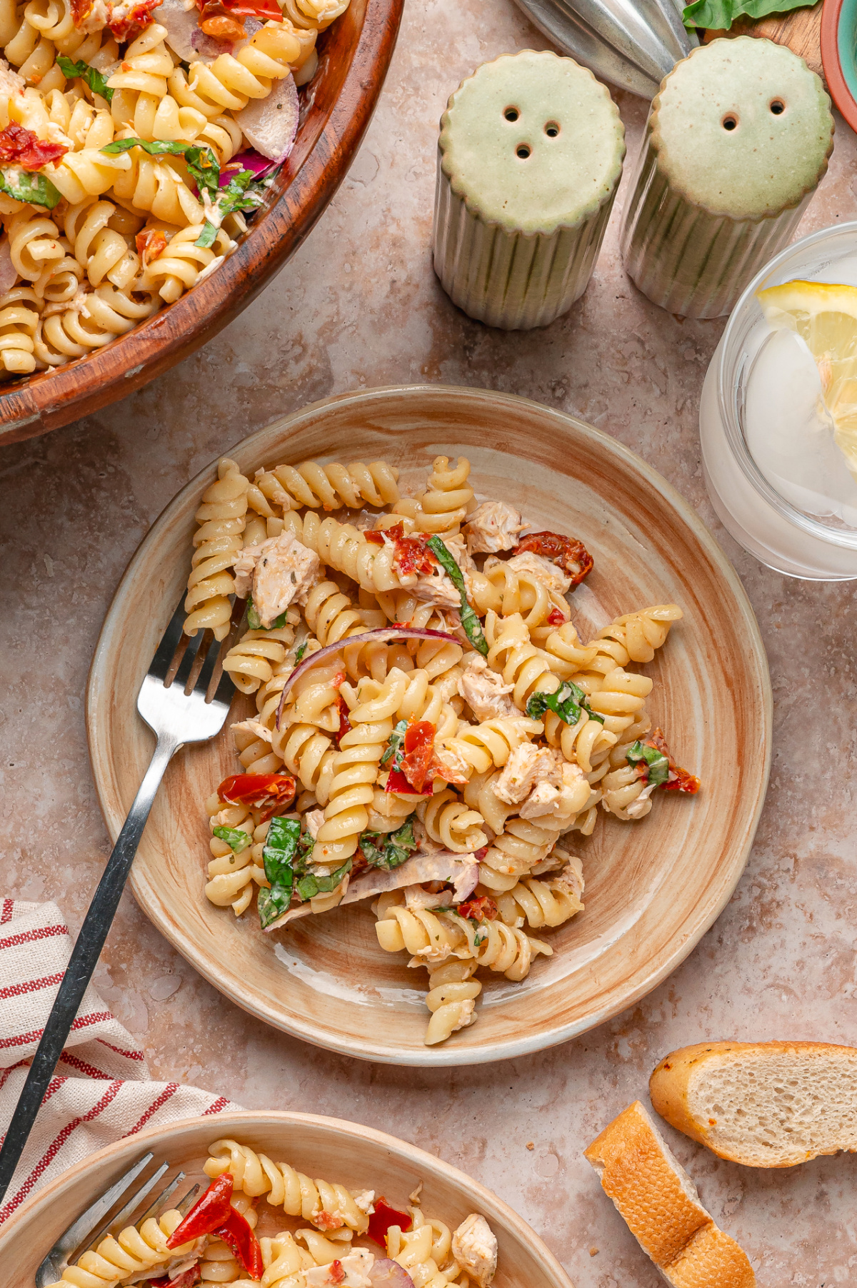 Plates of Sun-Dried Tomato Chicken Pasta Salad with rotini, basil, chicken, red onion, and chopped sun-dried tomatoes
