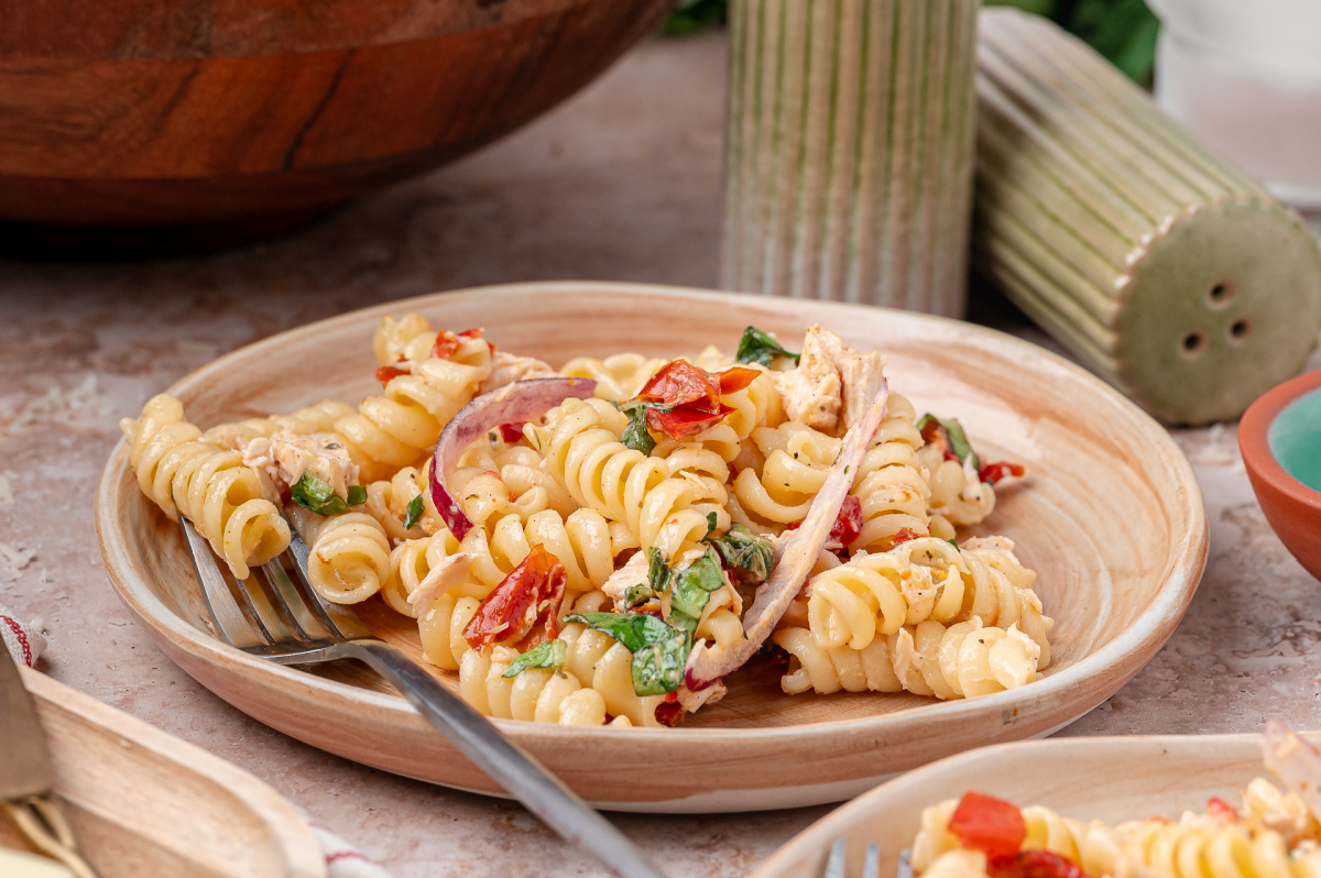 Serving of Sun-Dried Tomato Chicken Pasta Salad with rotini, basil, red onion, and rotisserie chicken on a small plate