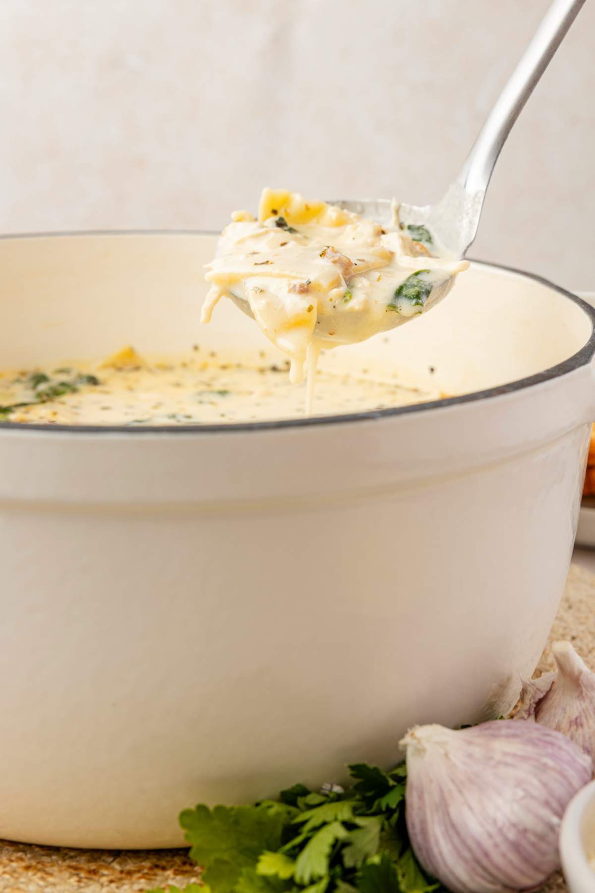 White chicken lasagna soup with ricotta, sausage, spinach, and lasagna noodles in creamy broth White chicken lasagna soup with ricotta, spinach, sausage, and lasagna noodles lifted from creamy broth with a ladle
