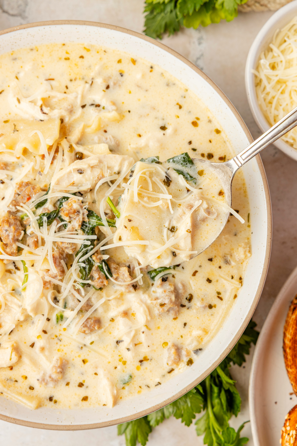 White Lasagna Soup with ricotta, spinach, sausage, and lasagna noodles in creamy Parmesan broth White Lasagna Soup with sausage, chicken, spinach, ricotta, and broken lasagna noodles in a creamy broth topped with Parmesan cheese