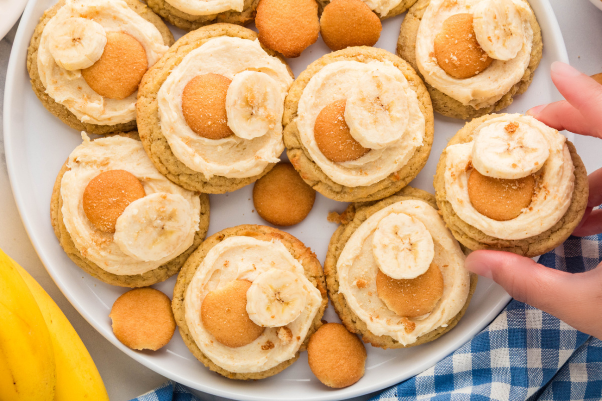 Close-up of banana pudding cookies with brown butter cream cheese frosting, mini vanilla wafers, and fresh banana slices.