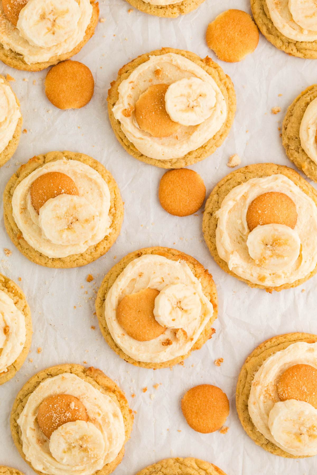 Overhead view of frosted banana pudding cookies topped with mini vanilla wafers and fresh banana slices.