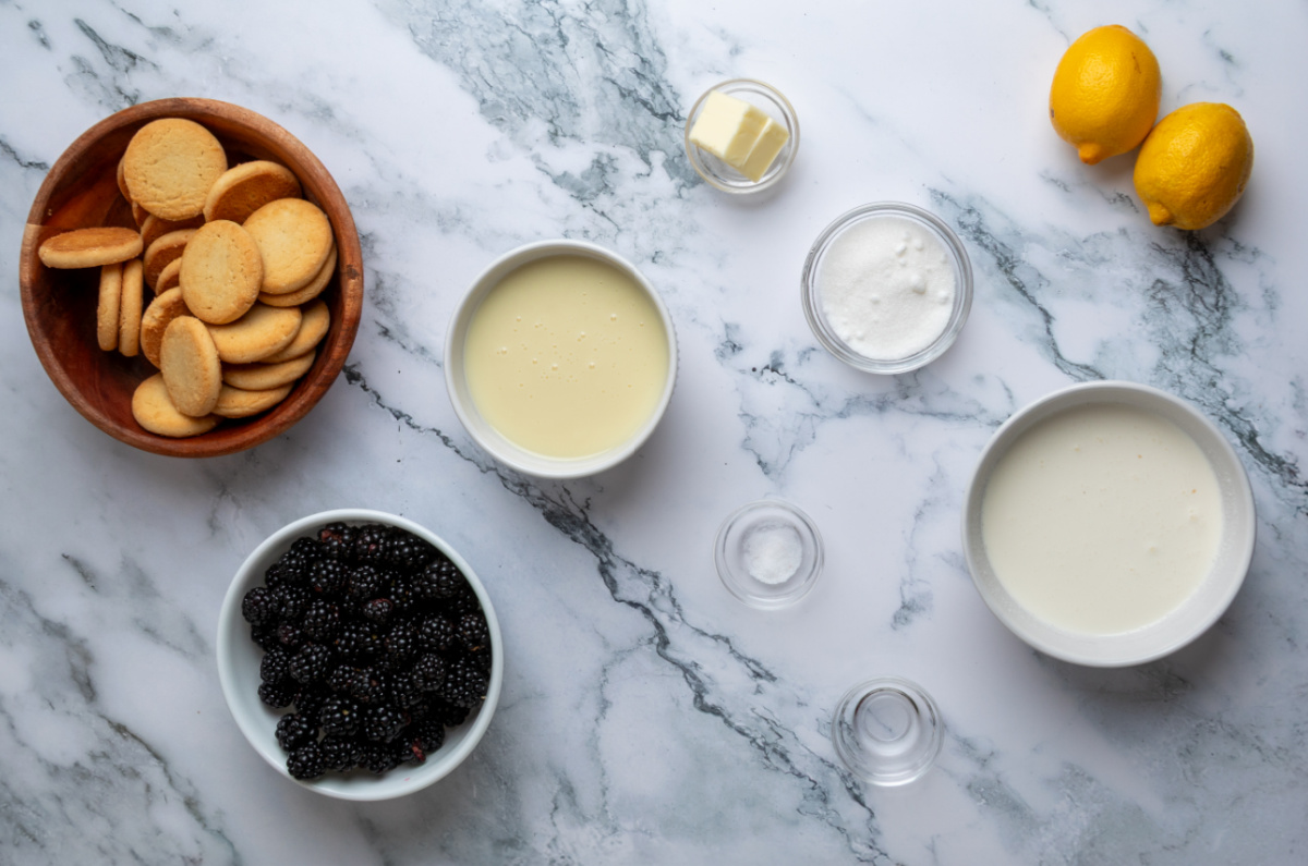 Everything you need to make homemade Blackberry Crumble à la Mode Ice Cream, including fresh blackberries, lemon, and buttery shortbread cookies. Ingredients for homemade no-churn blackberry ice cream including blackberries, heavy cream, sweetened condensed milk, shortbread cookies, lemons, butter, sugar, almond extract, and salt.