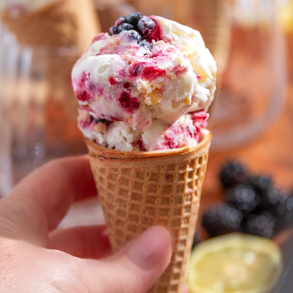 Blackberry Crumble à la Mode Ice Cream in a waffle cone with thick blackberry ribbons, buttery shortbread crumble, and fresh blackberries.
