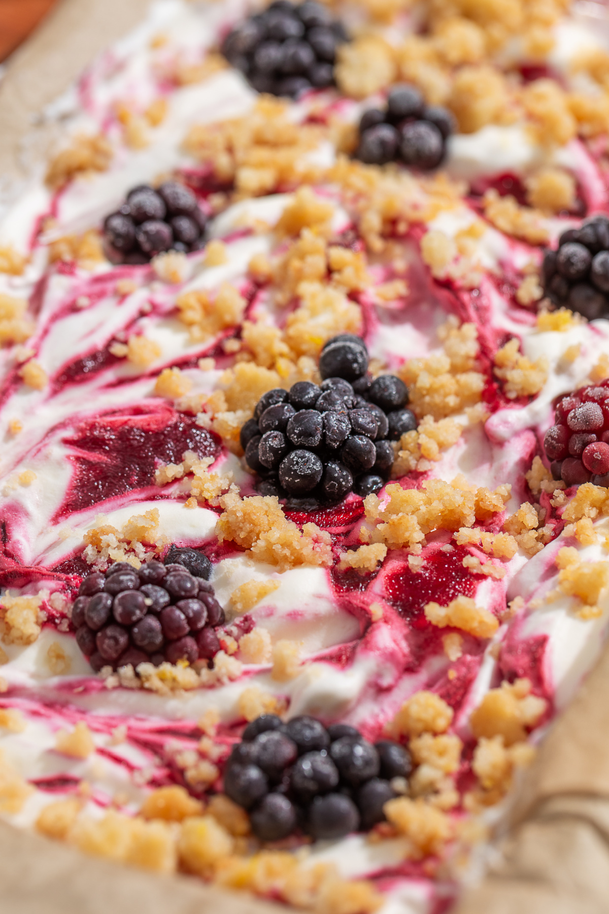 The thick blackberry swirl and buttery shortbread crumble make every bite taste like blackberry crumble à la mode. Close-up of homemade no-churn blackberry ice cream with thick blackberry swirls, buttery shortbread crumble, and whole blackberries.