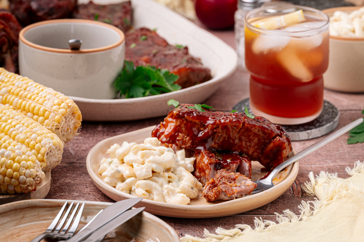 A plate of bourbon peach country style ribs served with creamy macaroni salad and fresh corn on the cob. Bourbon peach country style ribs served with macaroni salad and corn on the cob