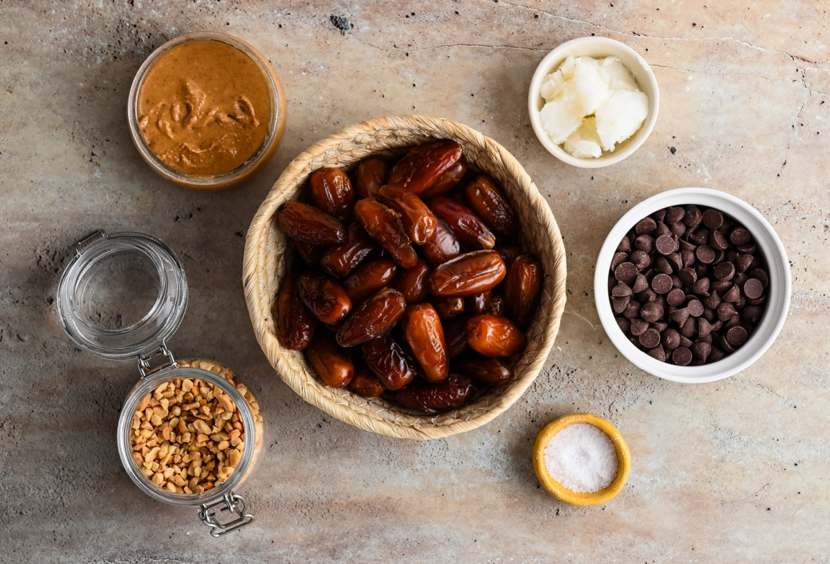 Simple ingredients for chocolate peanut butter stuffed dates Ingredients for chocolate peanut butter stuffed dates including Medjool dates, peanut butter, dark chocolate, peanuts, coconut oil, and flaky sea salt