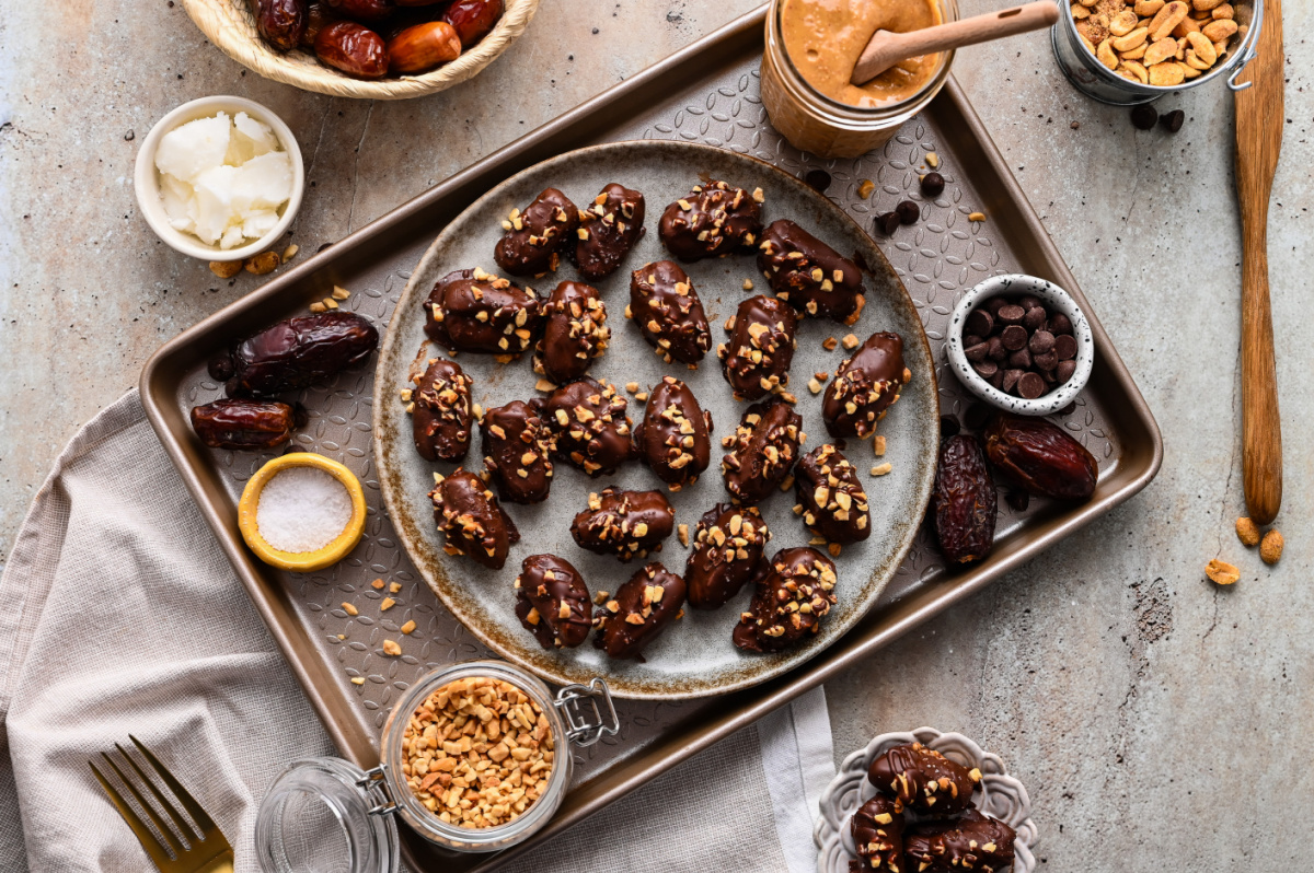 Overhead serving platter of chocolate peanut butter stuffed dates Overhead view of chocolate peanut butter stuffed dates topped with chopped peanuts and flaky sea salt