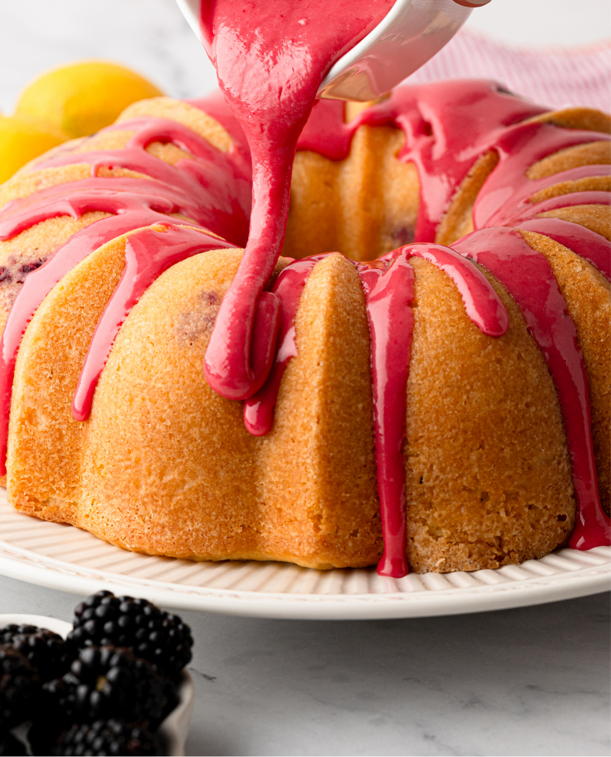Pouring fresh blackberry glaze over the cooled Bundt cake Fresh blackberry glaze being poured over a lemon Bundt cake