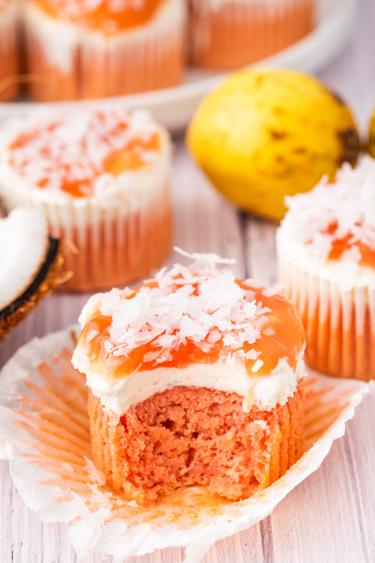 Guava glazed cream cheese cupcake topped with cream cheese frosting, guava glaze, and shredded coconut