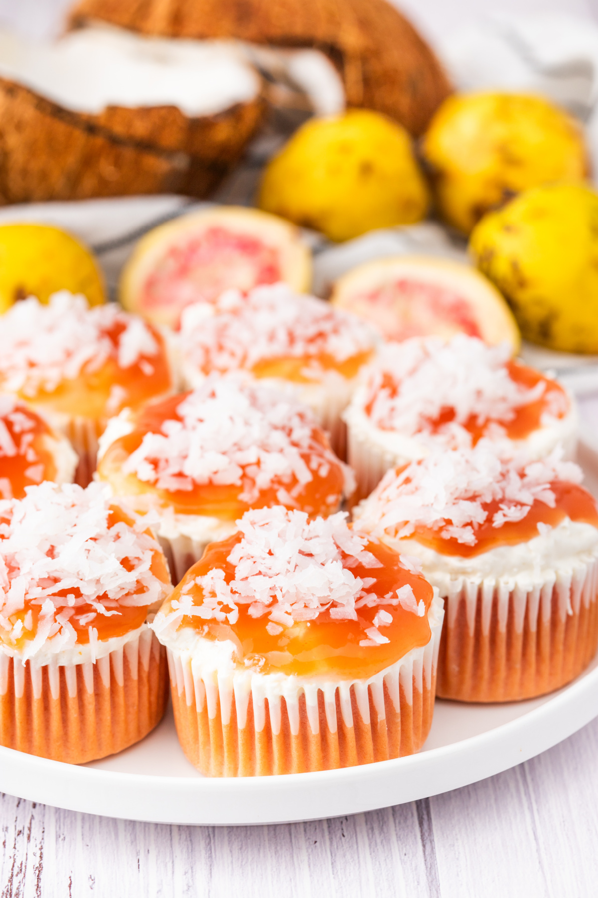 Plate of guava glazed cream cheese cupcakes topped with coconut and guava glaze