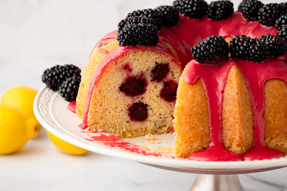 Interior of lemon blackberry Bundt cake with blackberries baked into every slice Slice removed from lemon blackberry Bundt cake showing whole blackberries baked throughout the cake