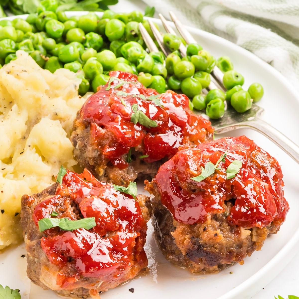Three mini meatloaves topped with tomato glaze on a dinner plate