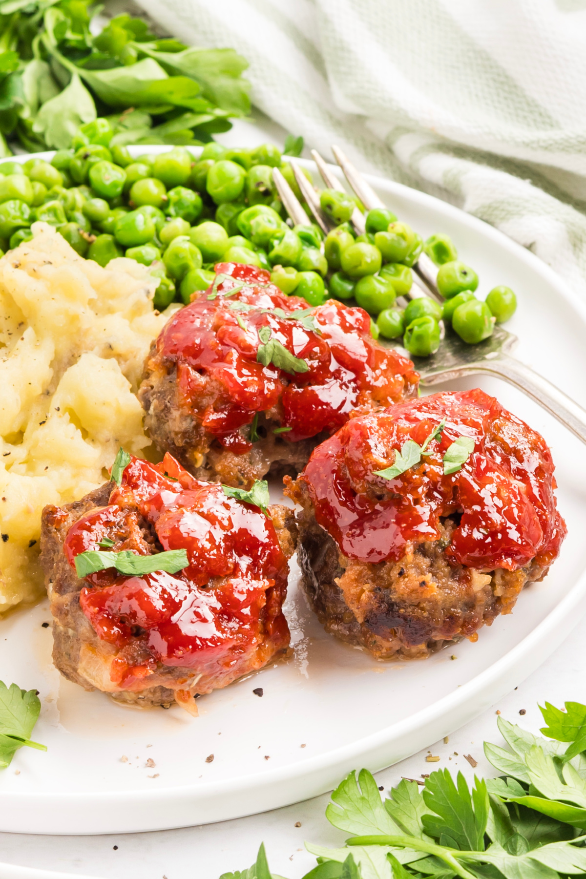 Individual mini meatloaves served with mashed potatoes and peas Mini meatloaf with tomato glaze served with mashed potatoes and peas