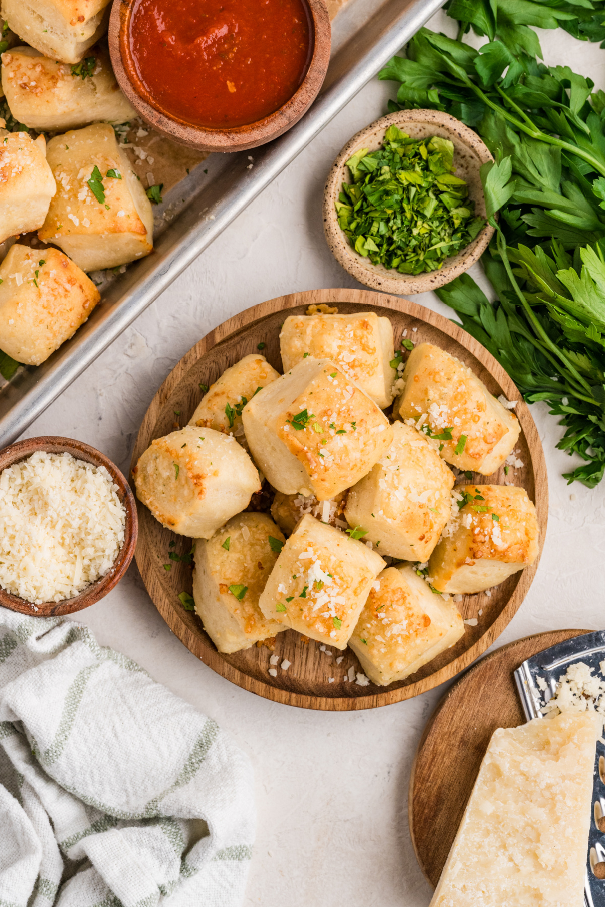Homemade Parmesan bread bites served with marinara sauce and extra Parmesan cheese Parmesan bread bites on a serving platter with marinara sauce, Parmesan cheese, and fresh parsley