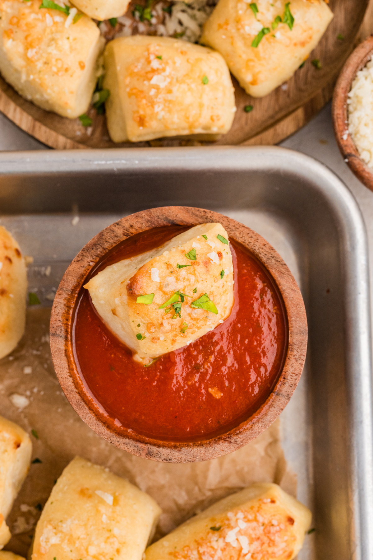A Parmesan bread bite dipped into marinara sauce for serving Parmesan bread bite served with marinara dipping sauce
