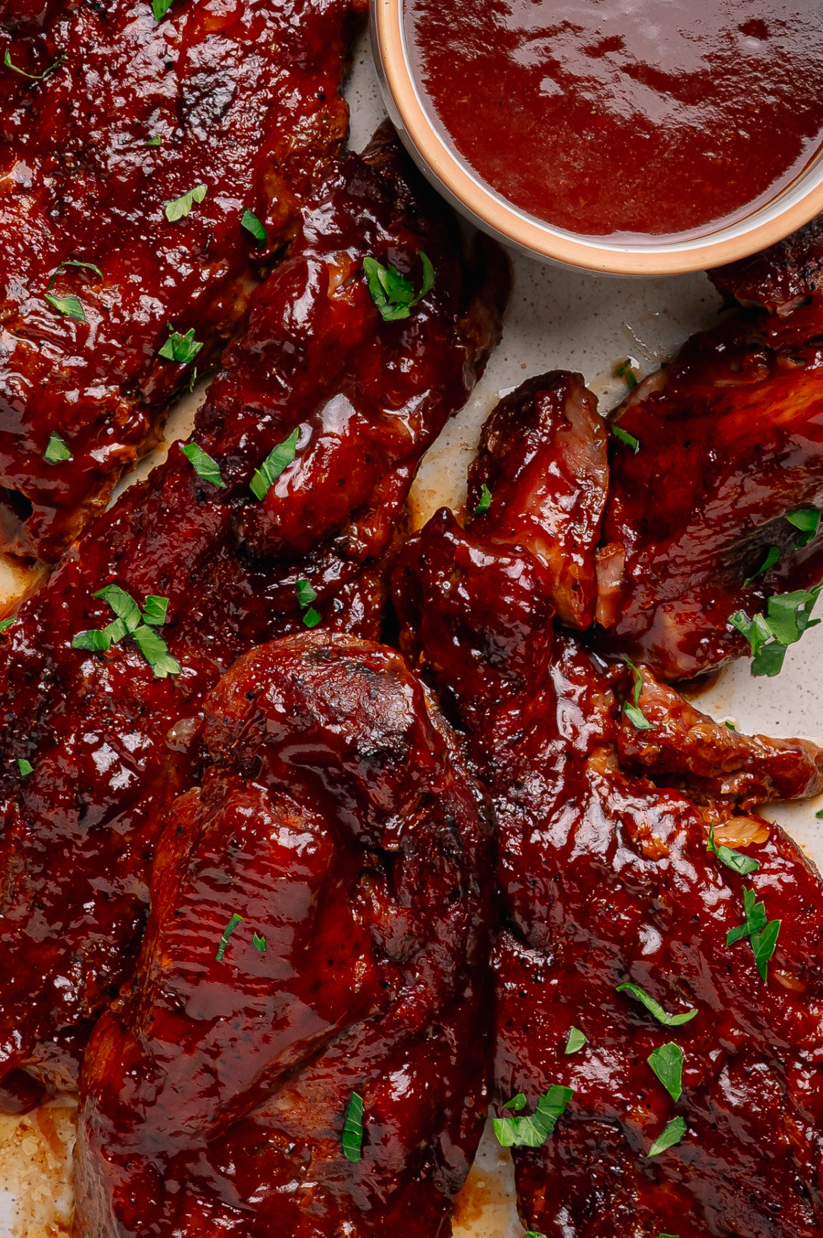 Close-up of country style pork ribs coated in a thick peach bourbon barbecue glaze with extra sauce for serving. Country style pork ribs coated in peach bourbon barbecue sauce with extra glaze served on the side