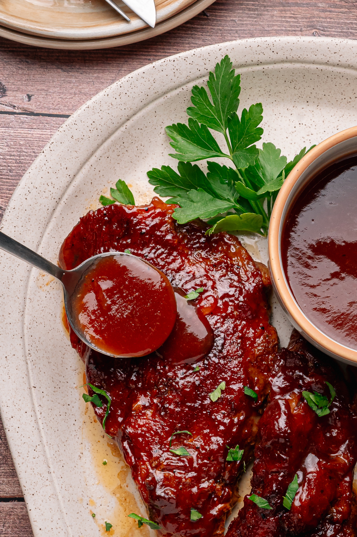 A spoonful of peach bourbon barbecue sauce being served over tender glazed country style pork ribs. Peach bourbon barbecue sauce being spooned over glazed country style pork ribs