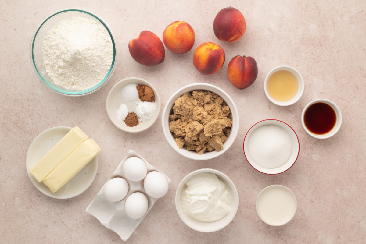 Everything needed to make peach cobbler Bundt cake with bourbon caramel. Ingredients for peach cobbler Bundt cake including peaches, brown sugar, sour cream, butter, eggs, flour, and spices.