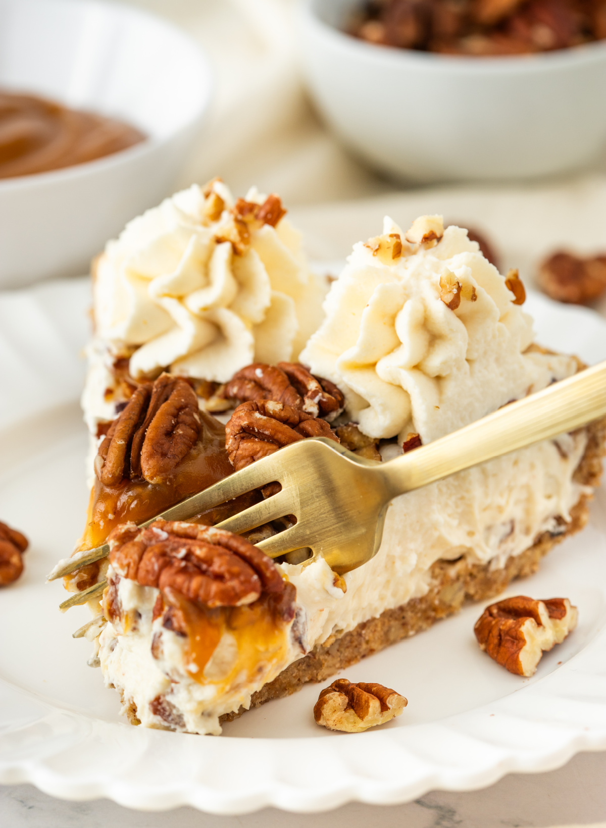 Chilled Pecan Pie Dessert Fork lifting a bite of pecan cream pie with toasted pecans, caramel drizzle, whipped cream, and pecan crust