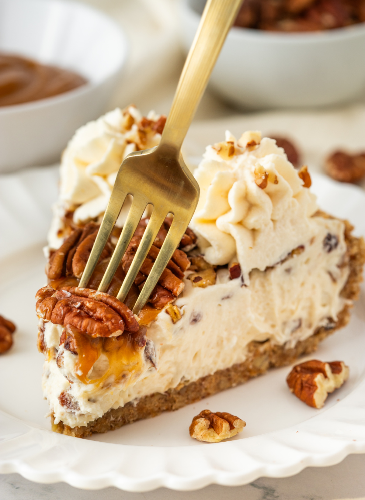 Southern Pecan Cream Pie Fork pressing into a slice of pecan cream pie with toasted pecans, caramel topping, whipped cream, and pecan crust