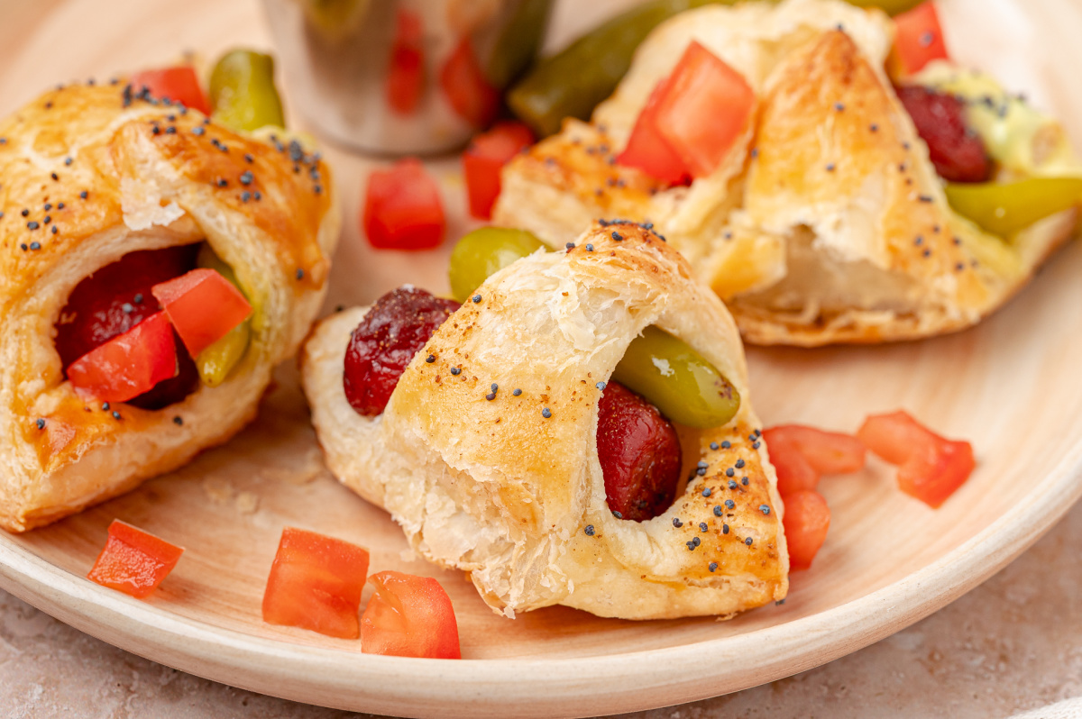 Sport peppers baked alongside beef cocktail franks give these pigs in a blanket their Chicago hot dog flavor. Close-up of flaky puff pastry wrapped around a beef cocktail frank and sport pepper.