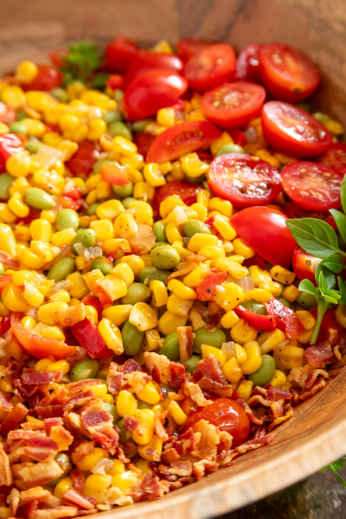 Close-up of succotash with edamame, sweet corn, tomatoes, peppers, and crispy bacon