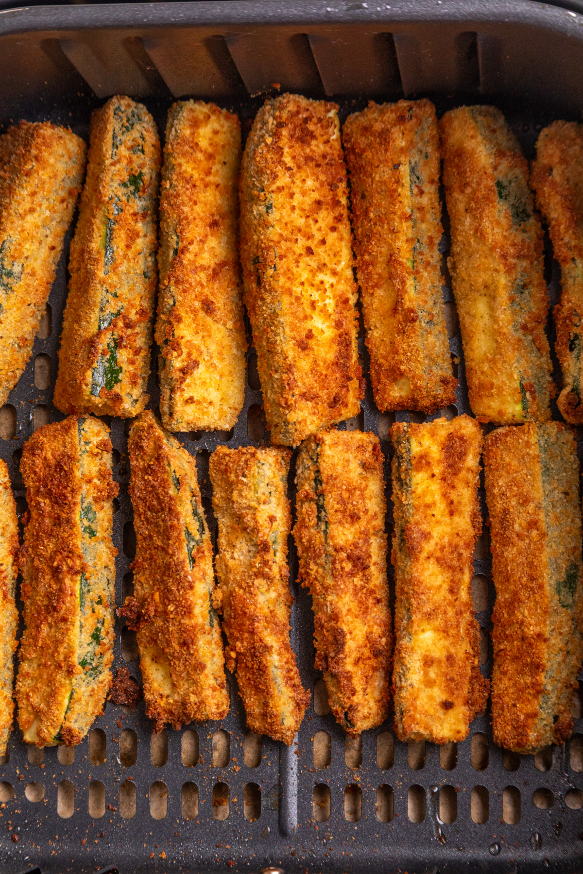 Air Fryer Zucchini Fries Cooking in the Air Fryer Breaded zucchini fries cooking in an air fryer basket until crisp and golden.