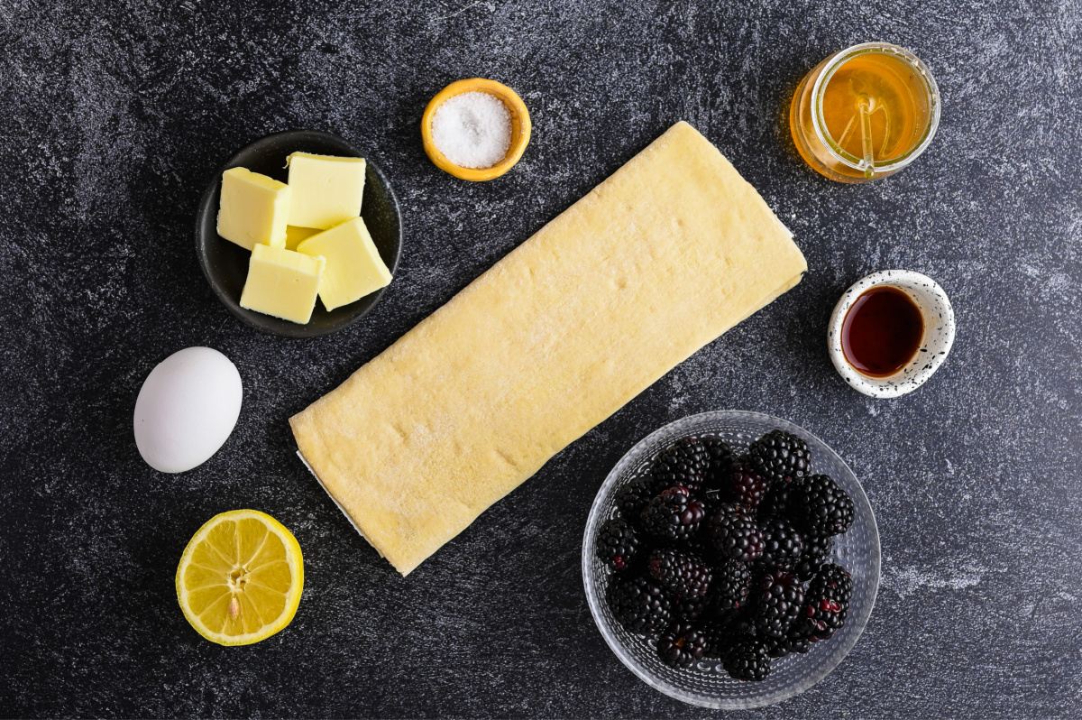 Everything you need to make Blackberry Puff Pastry Galette. Ingredients for blackberry puff pastry galette including fresh blackberries, puff pastry, honey, butter, lemon, vanilla, egg, and salt.