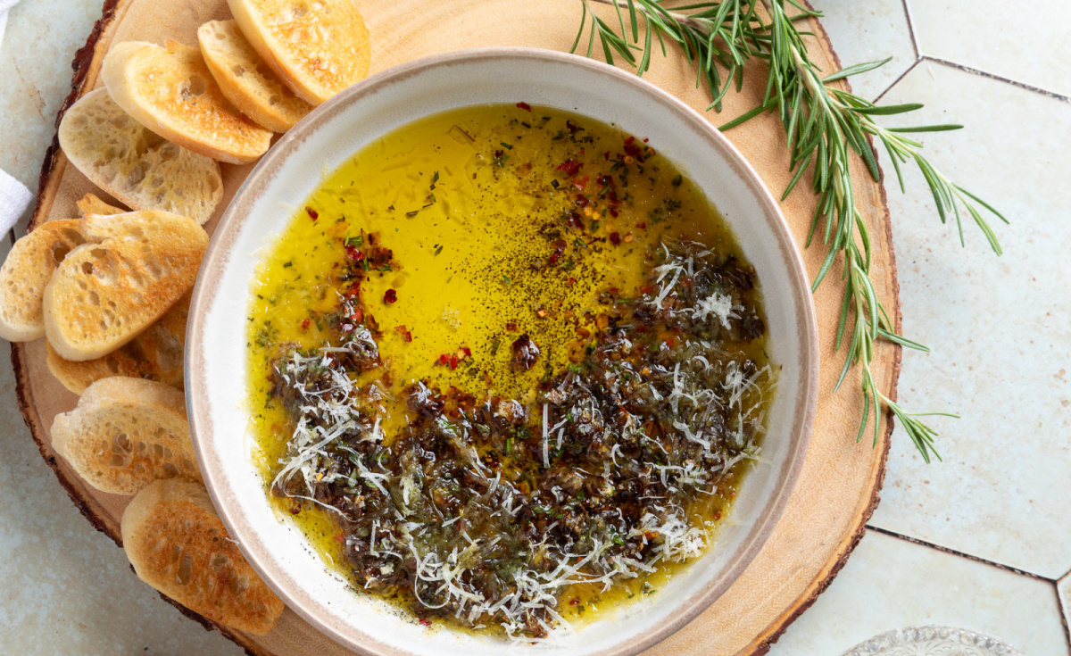 Bread Dipping Oil overhead view Overhead view of bread dipping oil with caramelized shallots, fresh herbs, Parmesan, and toasted baguette slices.