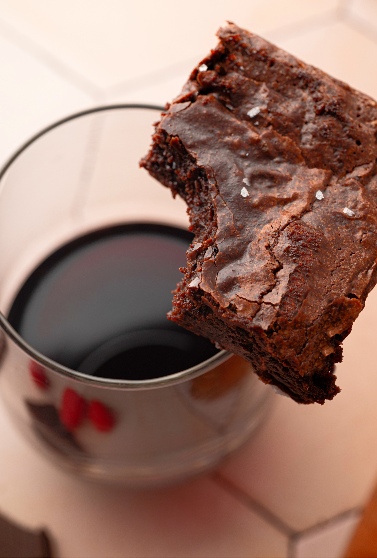 Cabernet Sauvignon Brown Butter Brownies with Cabernet Sauvignon Cabernet Sauvignon brown butter brownie held over a glass of Cabernet Sauvignon.