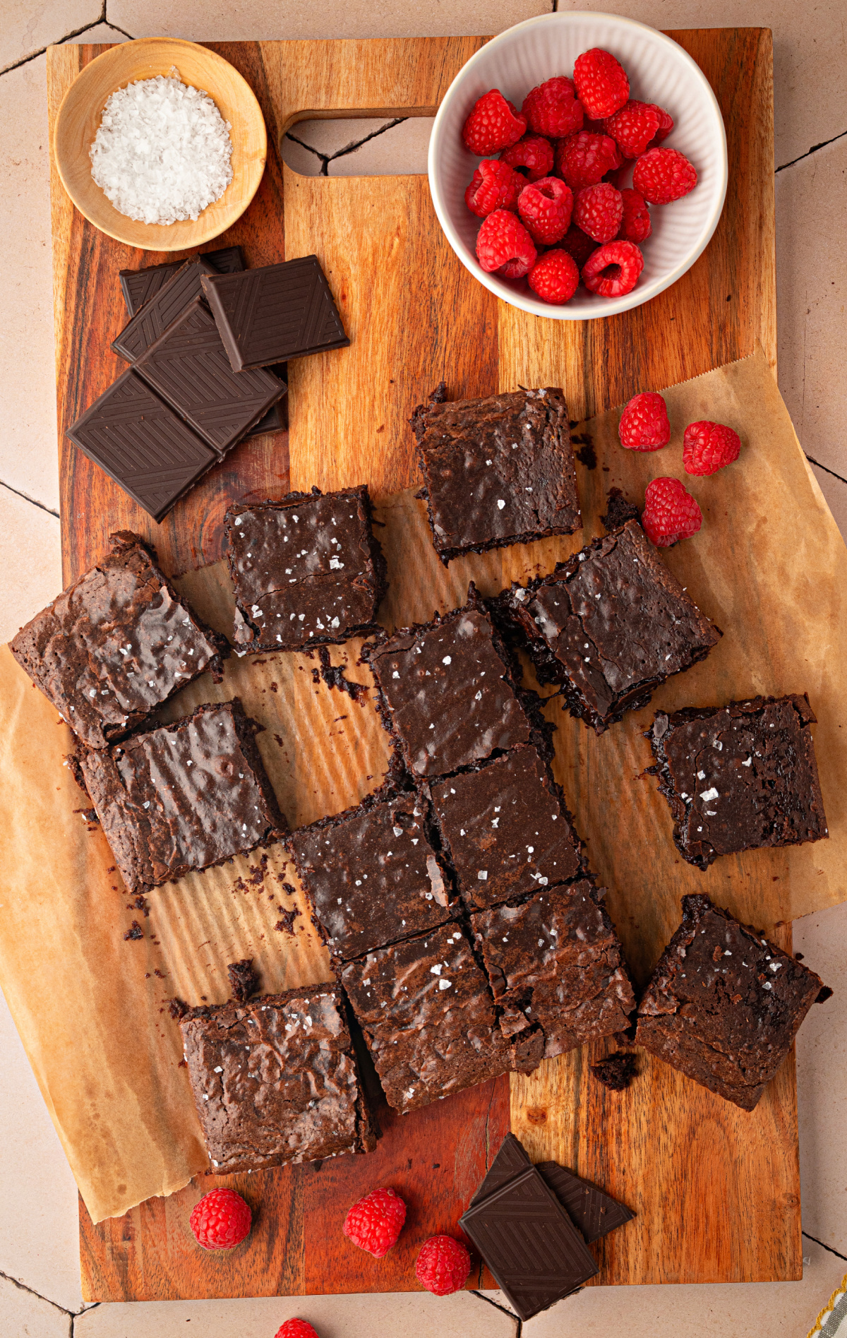 Cabernet Sauvignon Brown Butter Brownies ready to serve Cabernet Sauvignon brown butter brownies arranged on a wooden serving board with dark chocolate, flaky sea salt, and fresh raspberries.