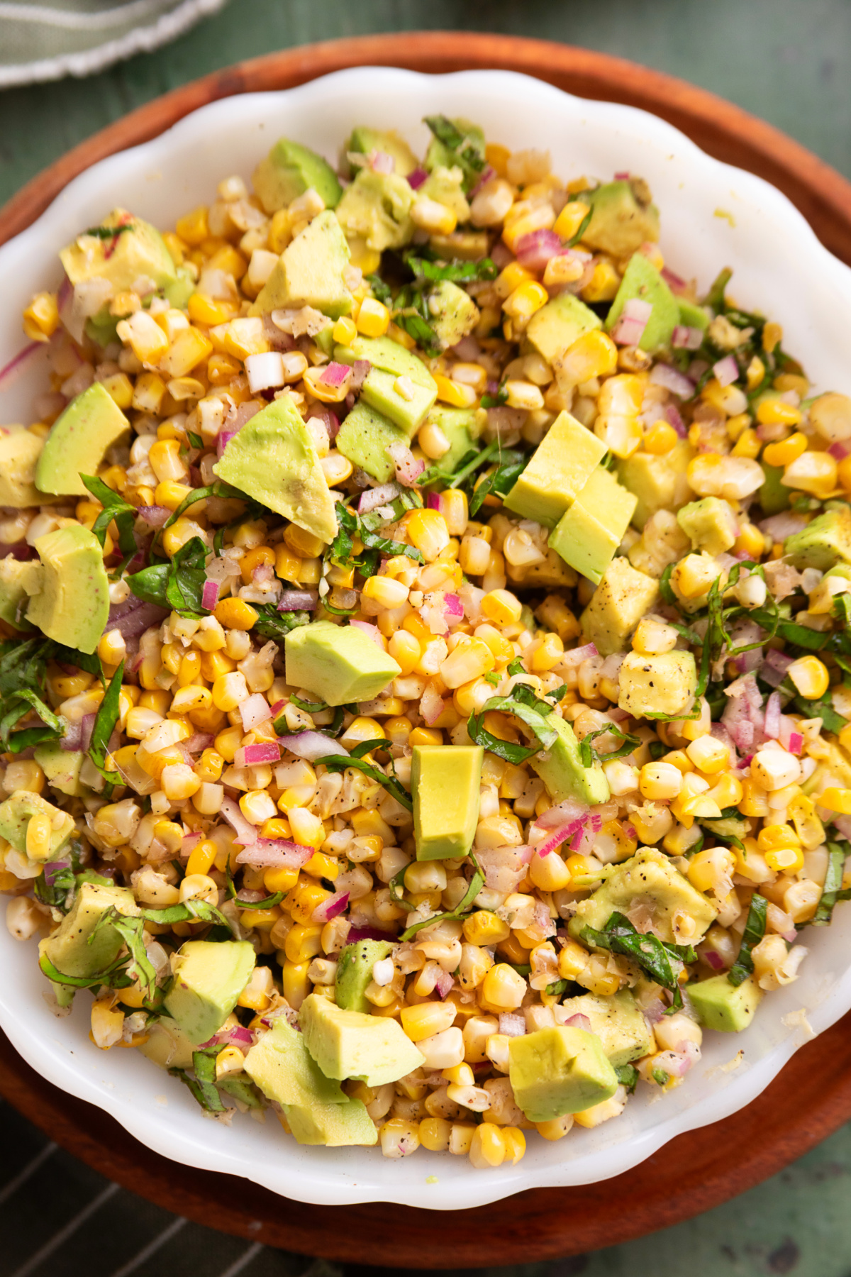 bowl of grilled corn salad with avocado, basil, and red onion.