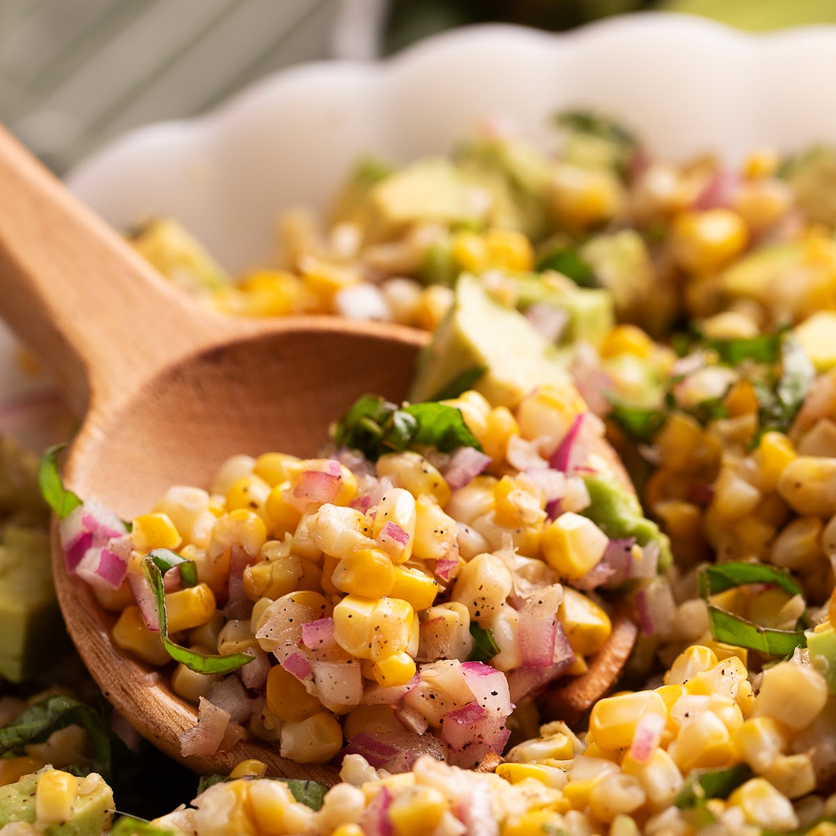 Close-up of grilled corn salad with avocado, basil, red onion, and lemon vinaigrette.