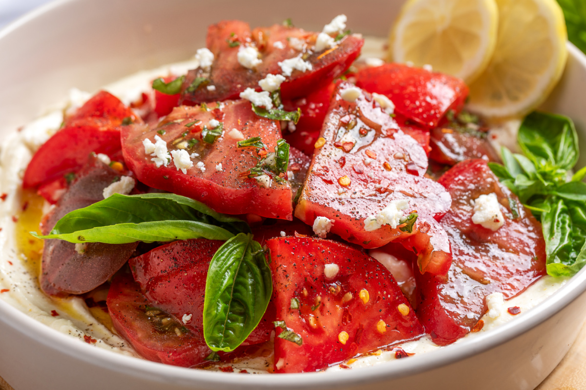A creamy whipped ricotta-feta base gives juicy heirloom tomatoes the perfect place to shine without overpowering their flavor. heirloom-tomato-salad-over-whipped-ricotta-feta-platter