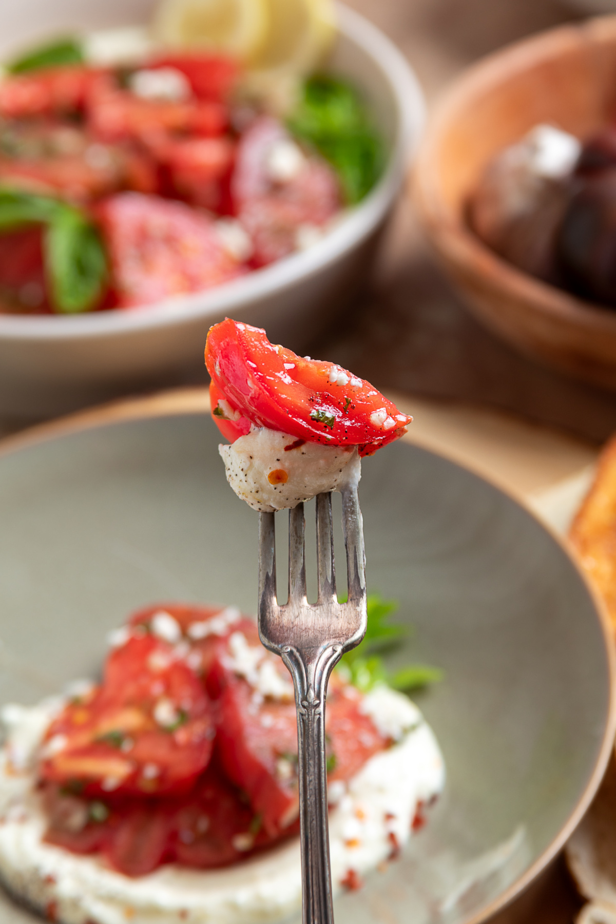 Every forkful combines juicy heirloom tomatoes, creamy whipped ricotta-feta, fresh basil, and a little lemon vinaigrette. Forkful of heirloom tomato salad with creamy whipped ricotta feta, fresh basil, and lemon vinaigrette.