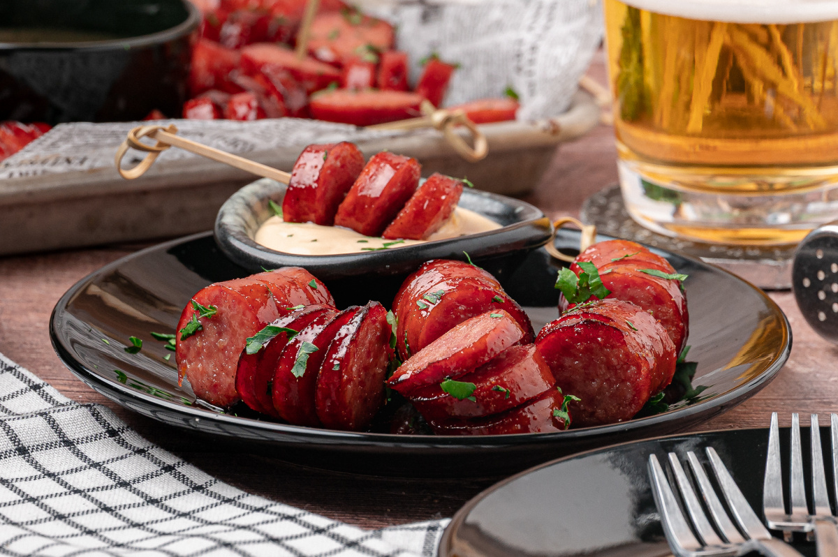 Honey garlic hasselback kielbasa bites served warm with creamy honey mustard for dipping. Honey garlic hasselback kielbasa bites on a plate with creamy honey mustard dipping sauce.