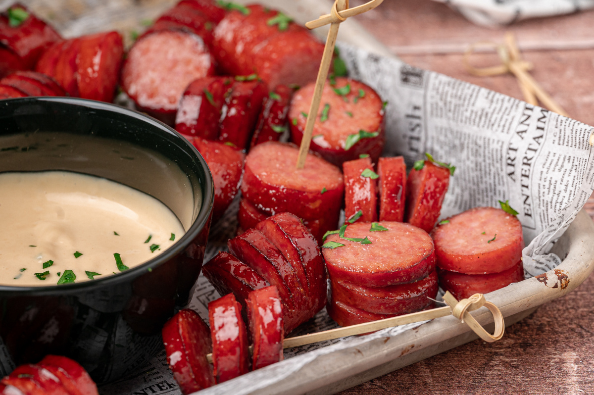 Sticky honey garlic hasselback kielbasa bites ready for dipping into creamy honey mustard. Honey garlic hasselback kielbasa bites served beside creamy honey mustard dipping sauce.