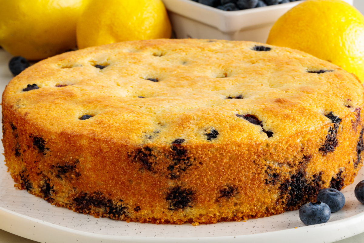 A closer look at the golden crust and blueberry-filled crumb of lemon blueberry cornbread. Side view of lemon blueberry cornbread with a golden crust and fresh blueberries baked throughout.