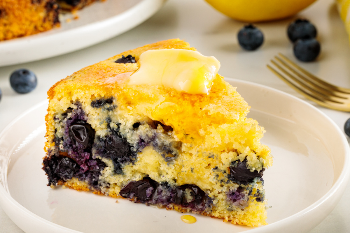 Warm lemon blueberry cornbread served with butter and honey for breakfast or brunch. Slice of lemon blueberry cornbread served with butter and honey, showing the tender crumb and fresh blueberries.