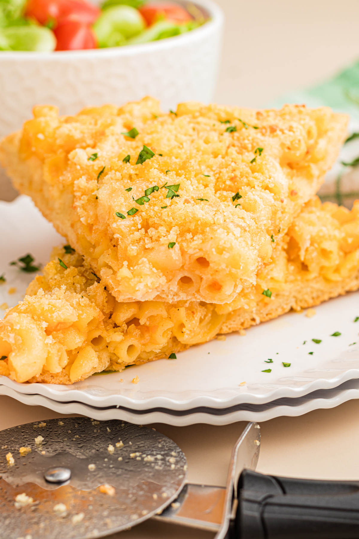 Mac and cheese pizza slices stacked on a white plate with creamy homemade macaroni and cheese, buttery breadcrumbs, and a crisp pizza crust.
