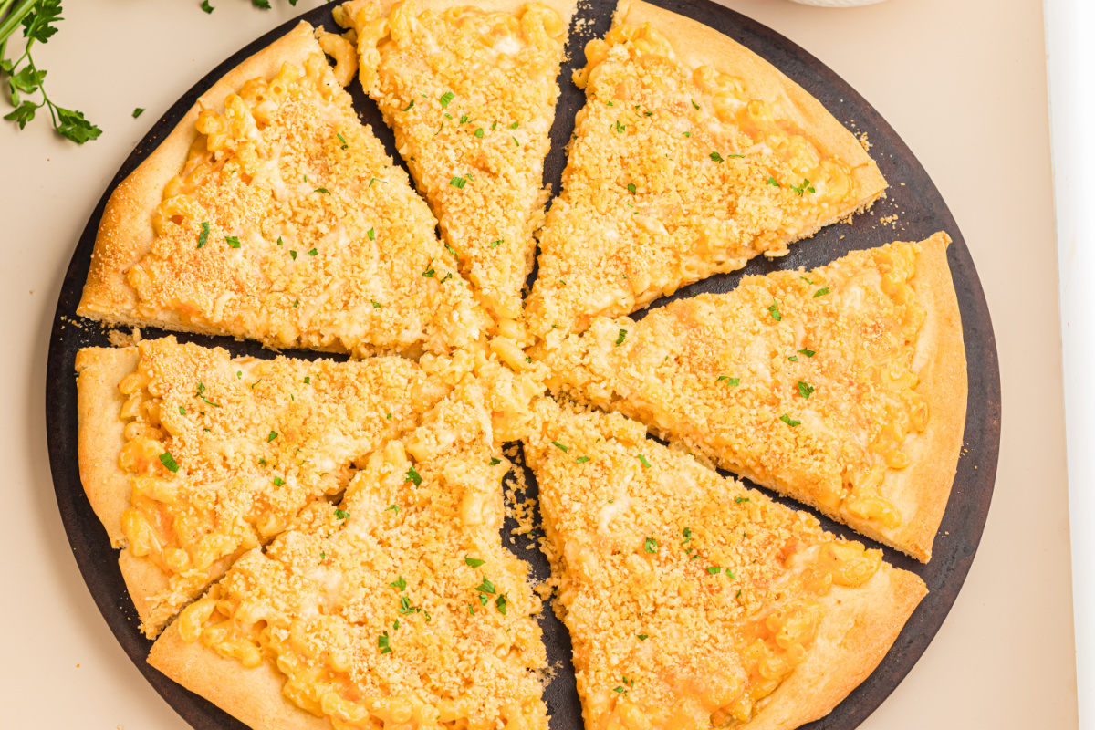 Overhead view of homemade mac and cheese pizza topped with buttery panko breadcrumbs, melted cheese, and sliced into eight pieces.