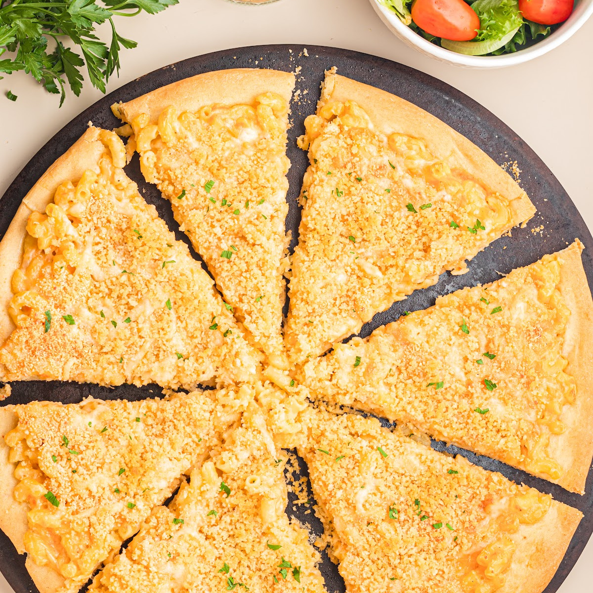 Homemade mac and cheese pizza topped with buttery panko breadcrumbs and sliced into eight pieces.