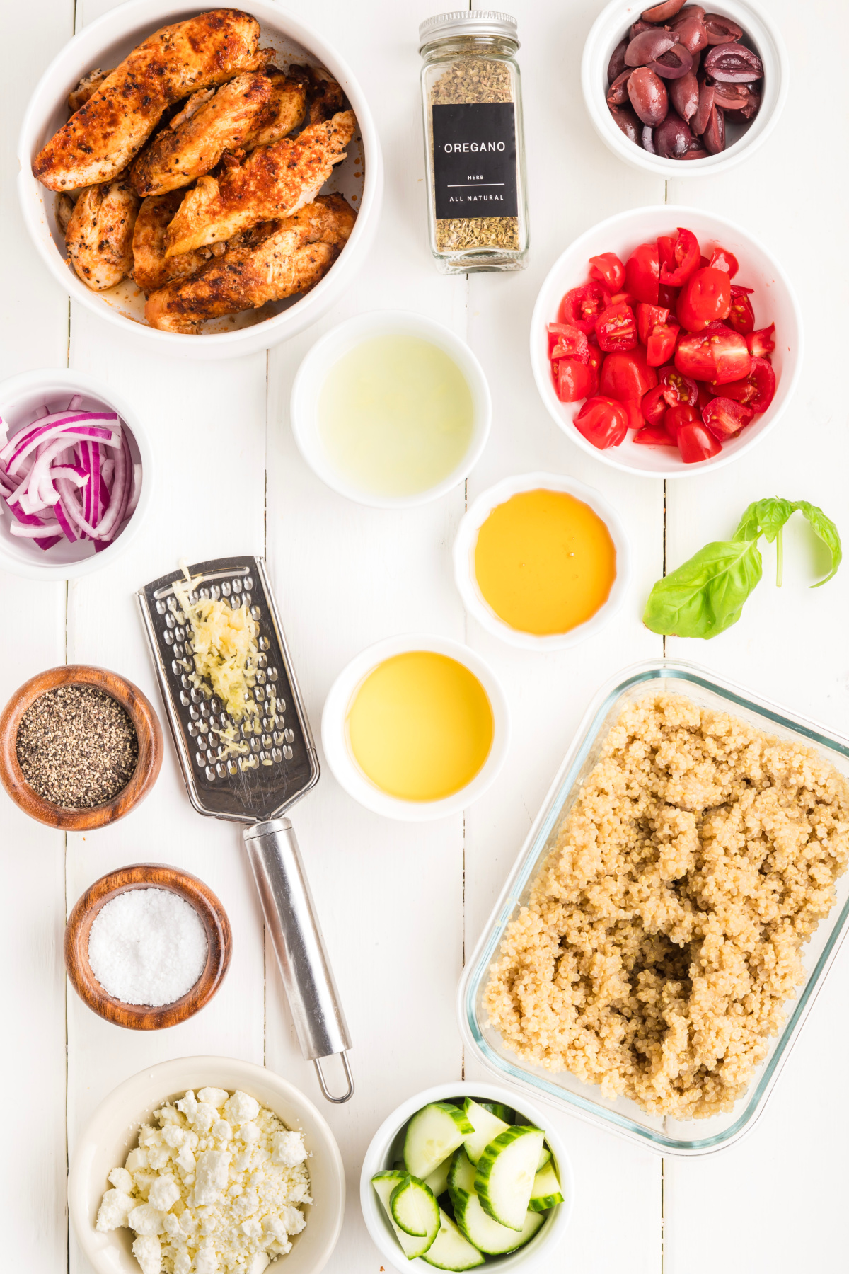 Mediterranean Chicken Bowl Ingredients Ingredients for Mediterranean chicken bowl including grilled chicken, cooked quinoa, cucumber, cherry tomatoes, Kalamata olives, feta, red onion, basil, lemon juice, olive oil, garlic, oregano, salt, pepper, and honey.