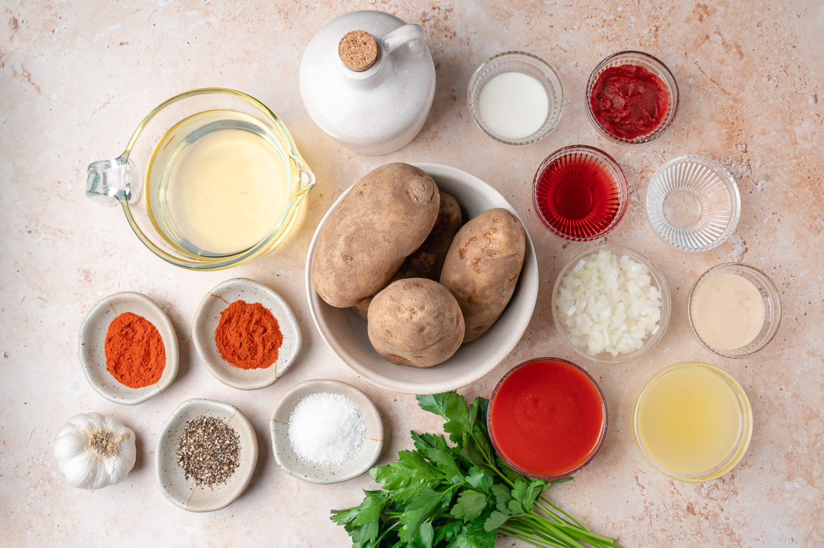 Patatas Bravas Ingredients Ingredients for patatas bravas including russet potatoes, tomato sauce, onion, garlic, smoked paprika, tomato paste, broth, vinegar, parsley, and oil.