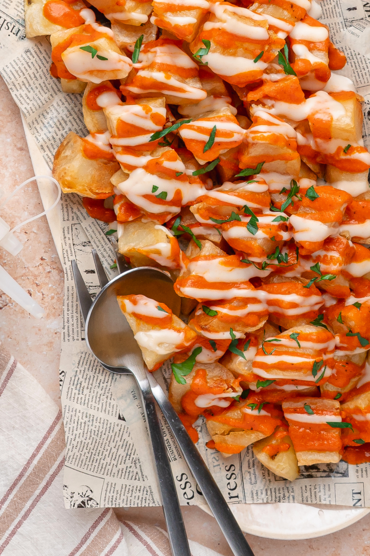 Patatas Bravas Patatas bravas topped with homemade bravas sauce, garlic aioli, and fresh parsley.